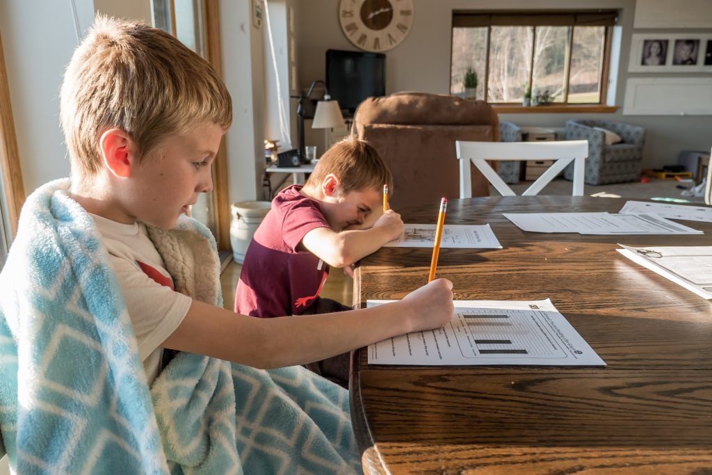 Two young boys doing homework at the table and helping with homework