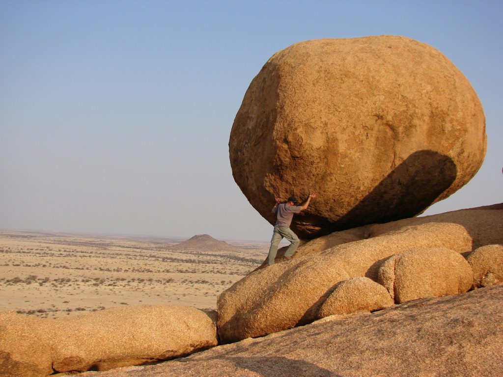 Man holding up a boulder with strength.