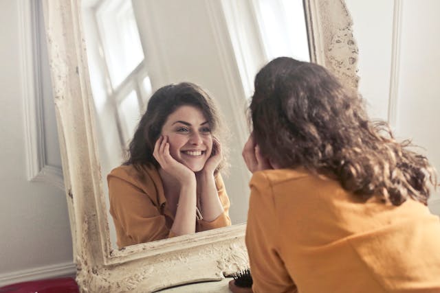 A woman looking at a mirror and smiling